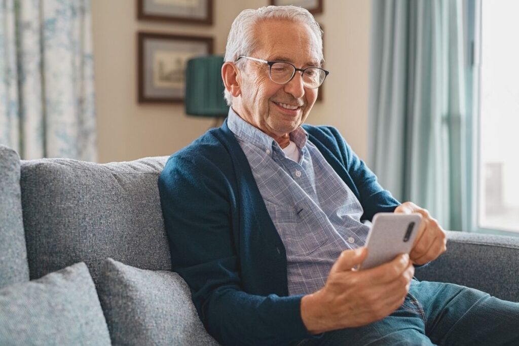 senior na kanapie z telefonem w ręku